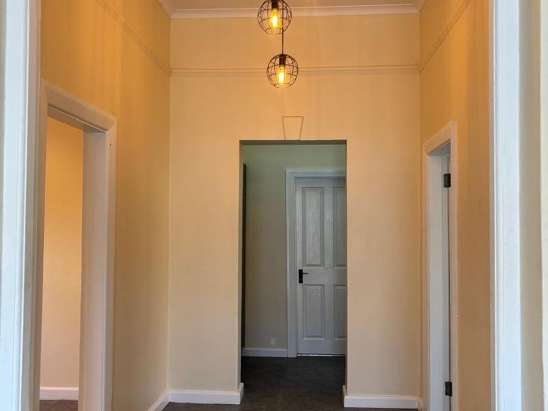 A bright and clean hallway featuring neutral walls, modern pendant lighting, and access to multiple rooms through internal doorways.