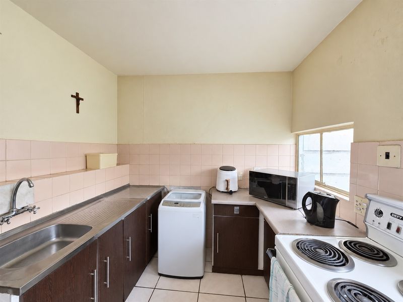 Functional kitchen featuring dark cabinetry, stainless steel sink, tiled backsplash, and an electric stove, offering a practical layout for daily meal preparation.