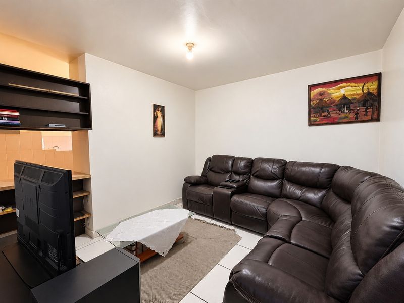 A living room featuring tiled flooring and built-in shelving units, providing a functional space for relaxation.