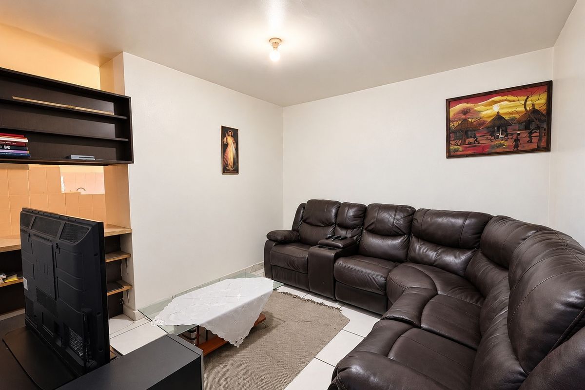 A living room featuring tiled flooring and built-in shelving units, providing a functional space for relaxation.