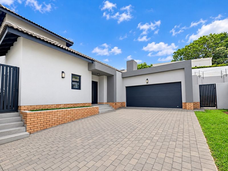 Modern front elevation featuring a paved driveway, double garage, and clean architectural lines with a brick-accented planter box.