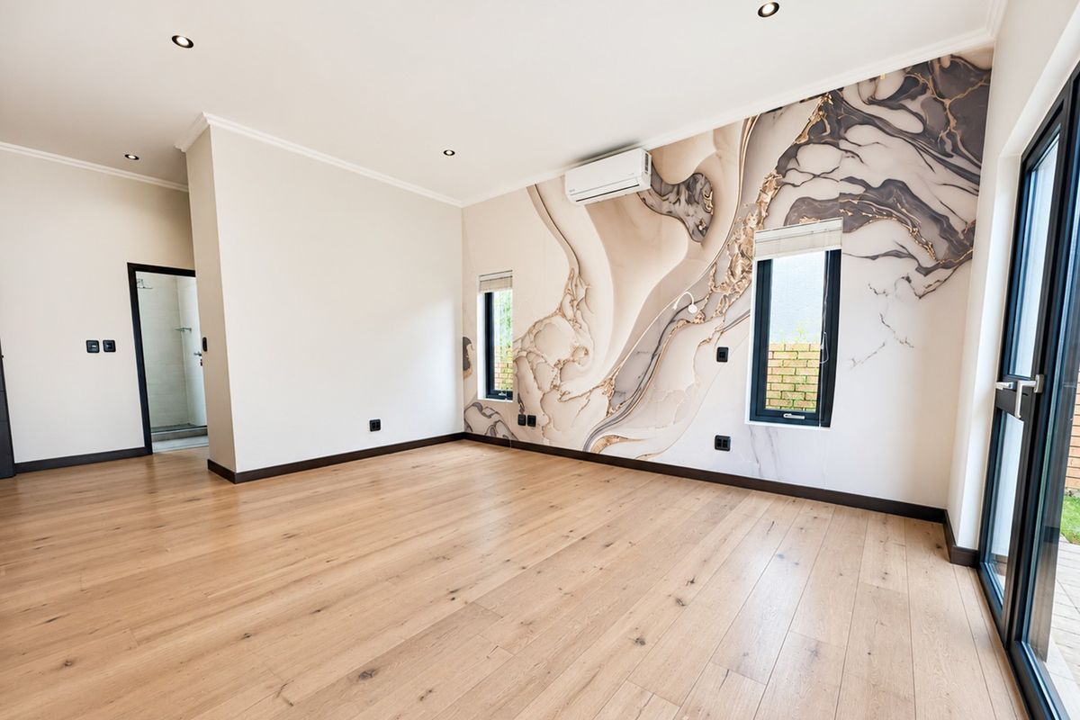 Spacious bedroom featuring light timber flooring, a striking marble-effect feature wall, recessed lighting, and direct access to the outdoors via a sliding glass door.