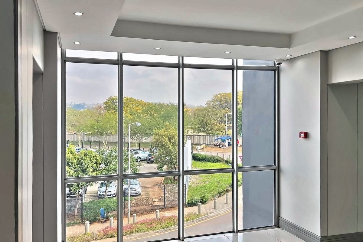A bright, modern commercial hallway featuring expansive floor-to-ceiling windows, recessed lighting, and a clean, professional finish.