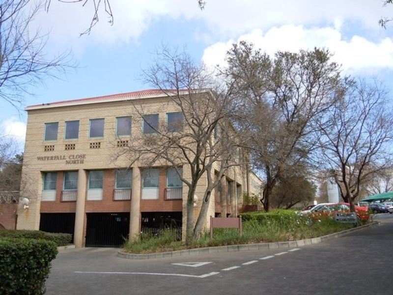 Front elevation of Waterfall Close North commercial building featuring a brick facade, tiled roof, and integrated undercover parking area.