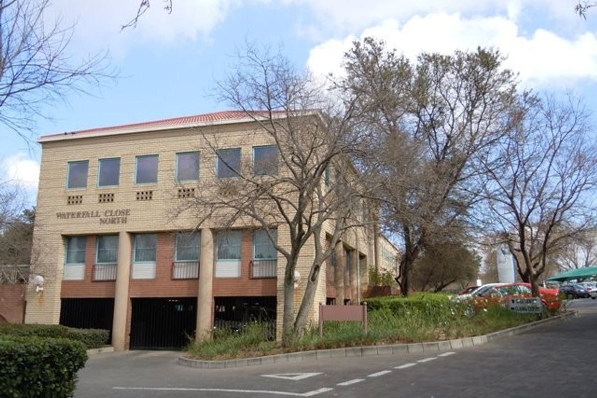 Front elevation of Waterfall Close North commercial building featuring a brick facade, tiled roof, and integrated undercover parking area.