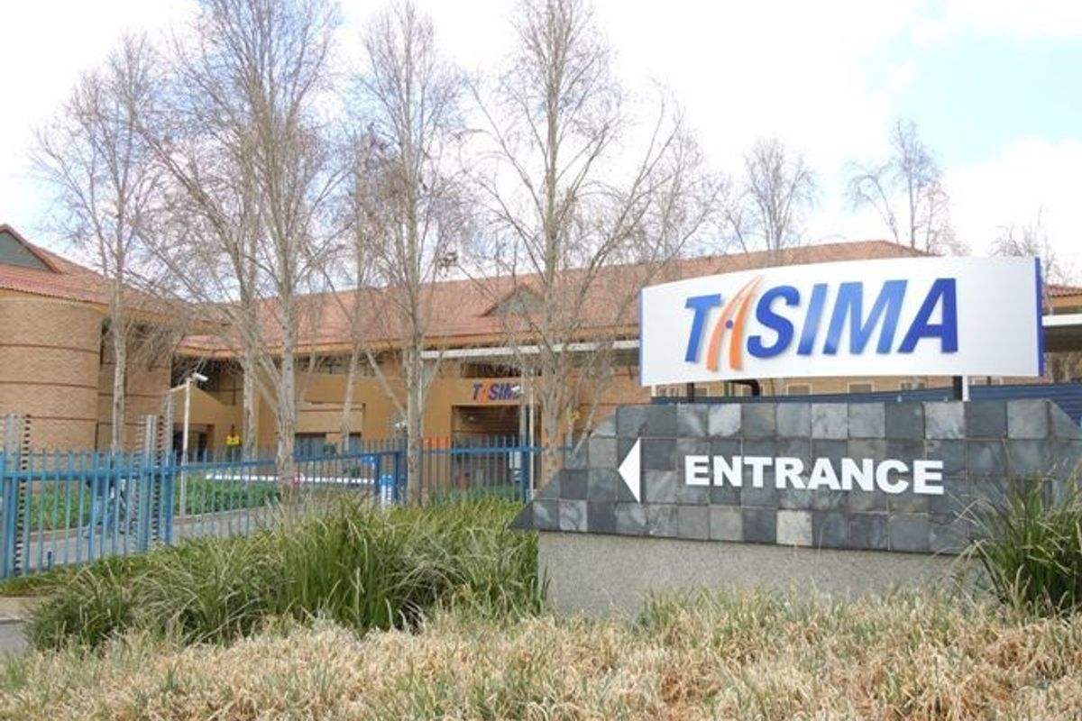 Front exterior view of the commercial property featuring a prominent entrance sign, brick facade, and secure perimeter fencing.