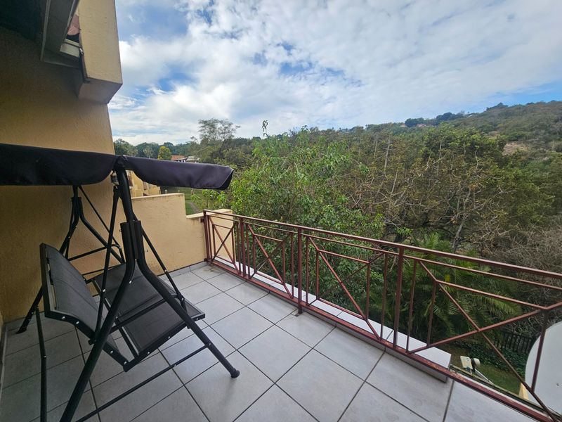 A private balcony featuring tiled flooring and a metal balustrade, offering scenic views of the surrounding trees and landscape.