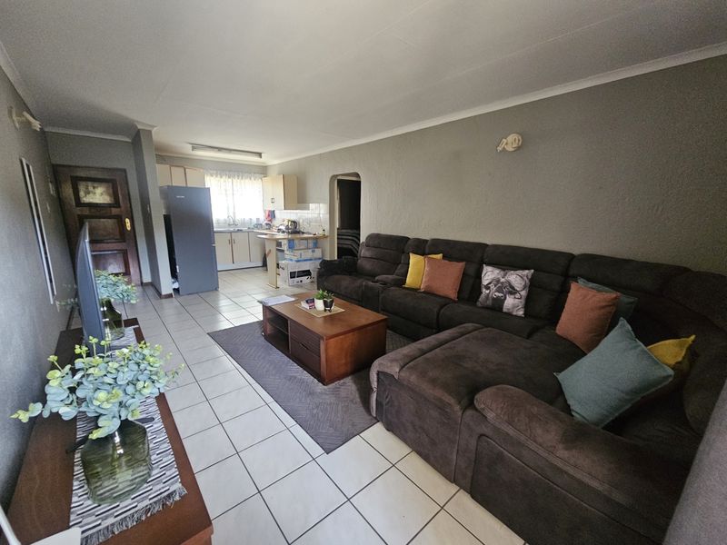 Open plan living area featuring tiled flooring and a functional kitchen space with built-in cabinetry.