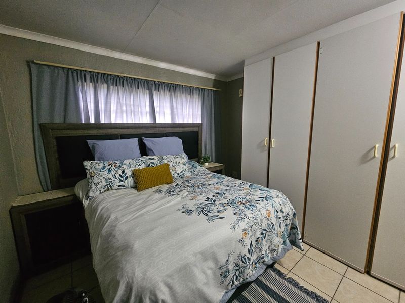 A functional bedroom featuring built-in cupboards and tiled flooring, providing a practical and comfortable living space.