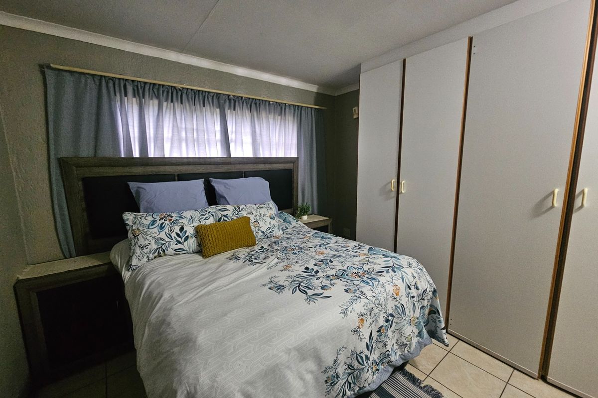 A functional bedroom featuring built-in cupboards and tiled flooring, providing a practical and comfortable living space.