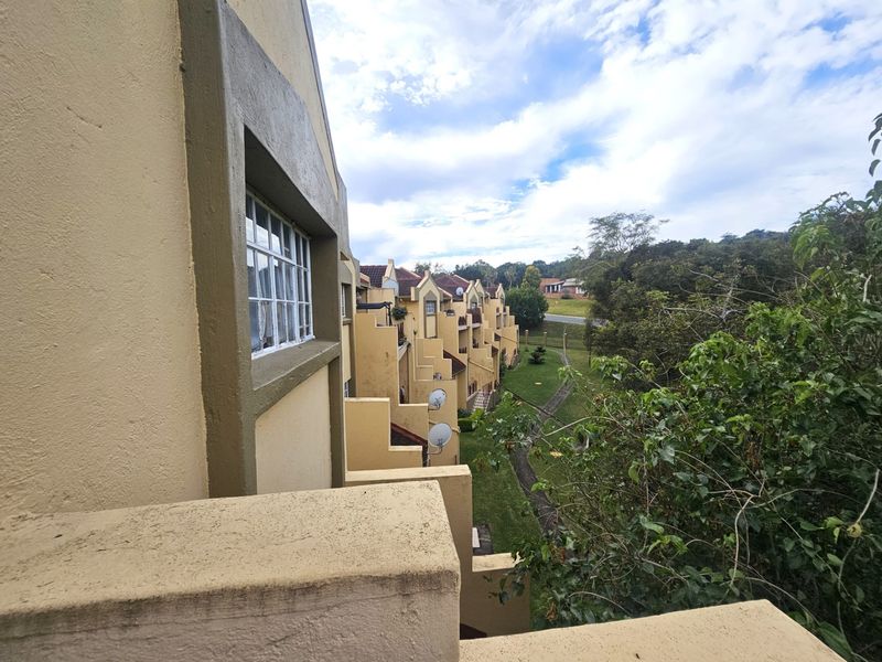 View of the rear building facade and balconies overlooking the communal garden area and surrounding landscape.