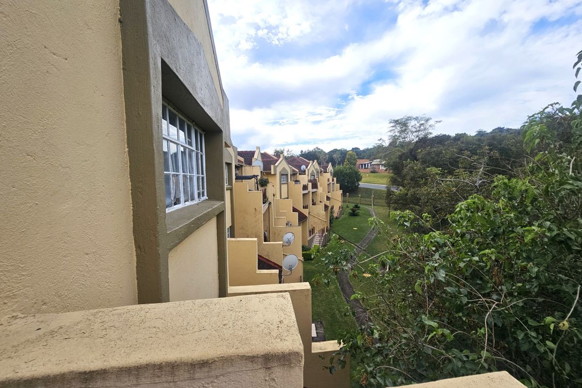 View of the rear building facade and balconies overlooking the communal garden area and surrounding landscape.