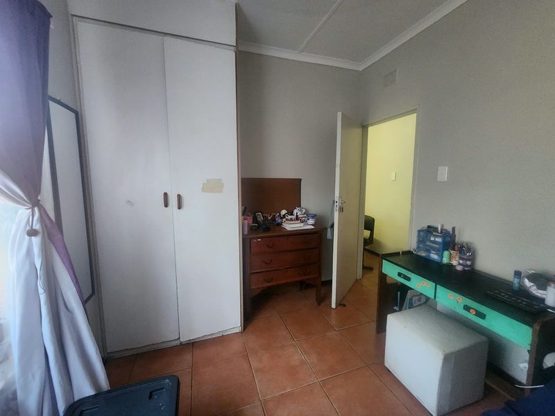 A bedroom featuring tiled flooring and a built-in wardrobe, offering a functional space that could benefit from cosmetic updates.