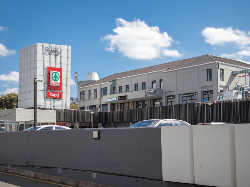 Exterior view of a commercial shopping center featuring a prominent branded tower, multi-level office and retail spaces, and integrated parking facilities.