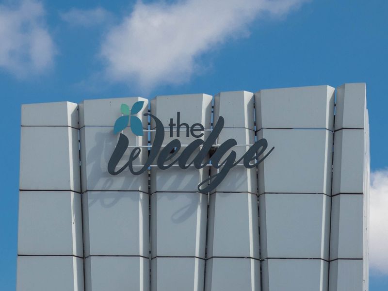 Close-up view of the modern building facade featuring the branded signage for The Wedge.