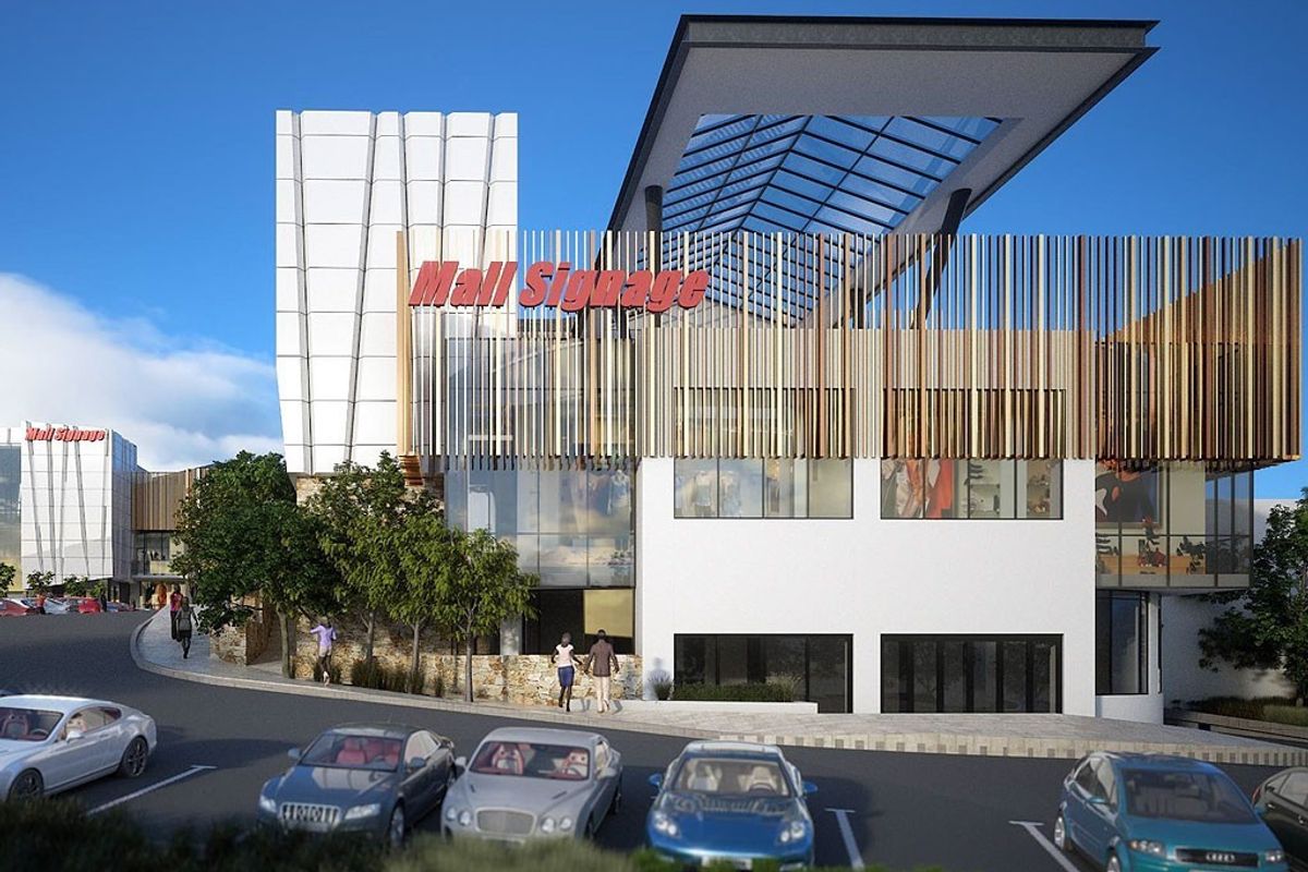 Modern commercial shopping center exterior featuring a prominent glass facade, cantilevered roof, and decorative vertical timber louvres with integrated parking.