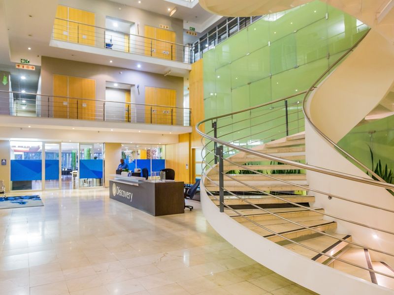 Spacious commercial atrium featuring a prominent spiral staircase, marble flooring, and a modern reception area with multi-level office access.