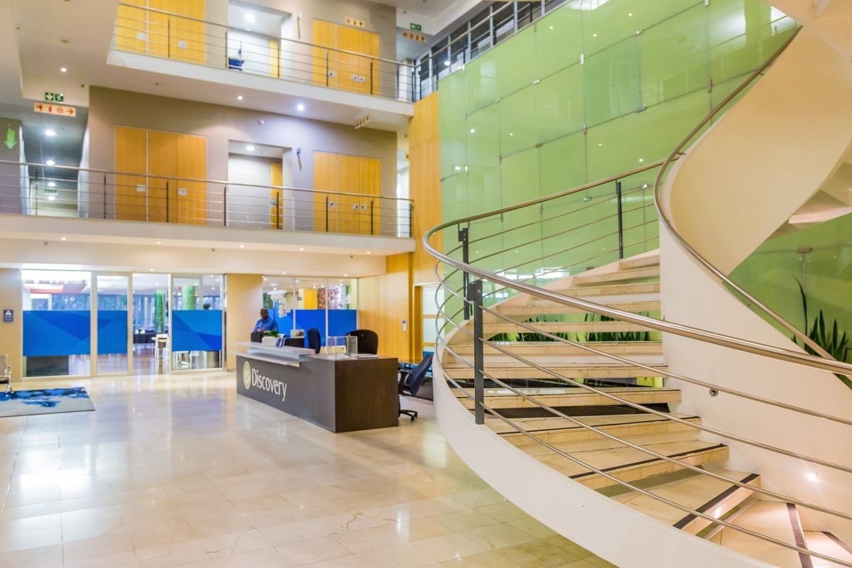 Spacious commercial atrium featuring a prominent spiral staircase, marble flooring, and a modern reception area with multi-level office access.