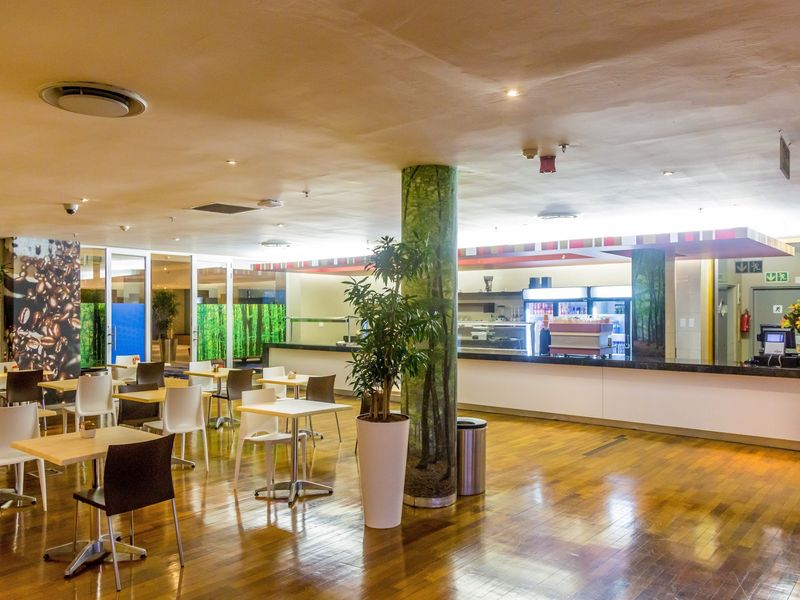Open-plan commercial dining and service area featuring polished hardwood flooring, a long service counter, and integrated ceiling lighting.