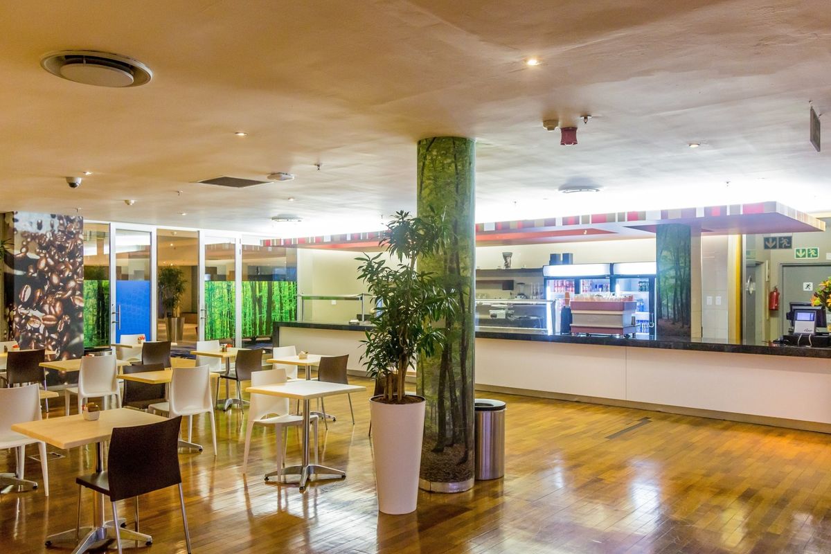 Open-plan commercial dining and service area featuring polished hardwood flooring, a long service counter, and integrated ceiling lighting.
