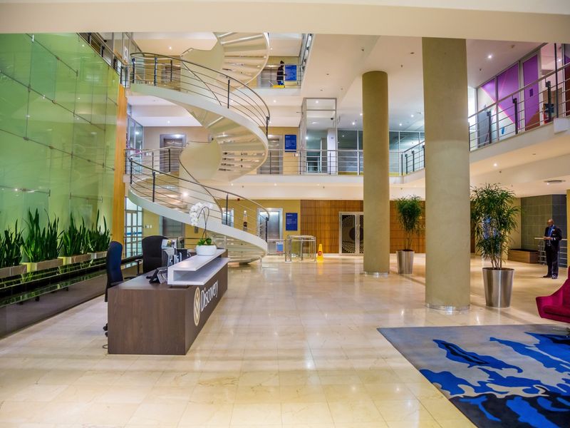 Spacious commercial lobby featuring a prominent spiral staircase, marble flooring, glass curtain wall, and a professional reception area with multi-level access.