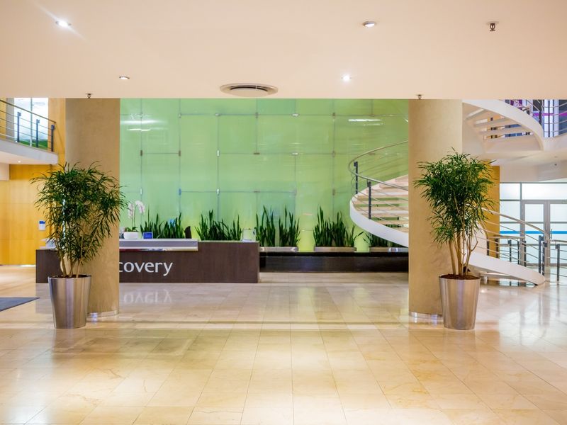 Modern commercial entrance lobby featuring a reception desk, a striking spiral staircase, and a large glass feature wall with integrated lighting.
