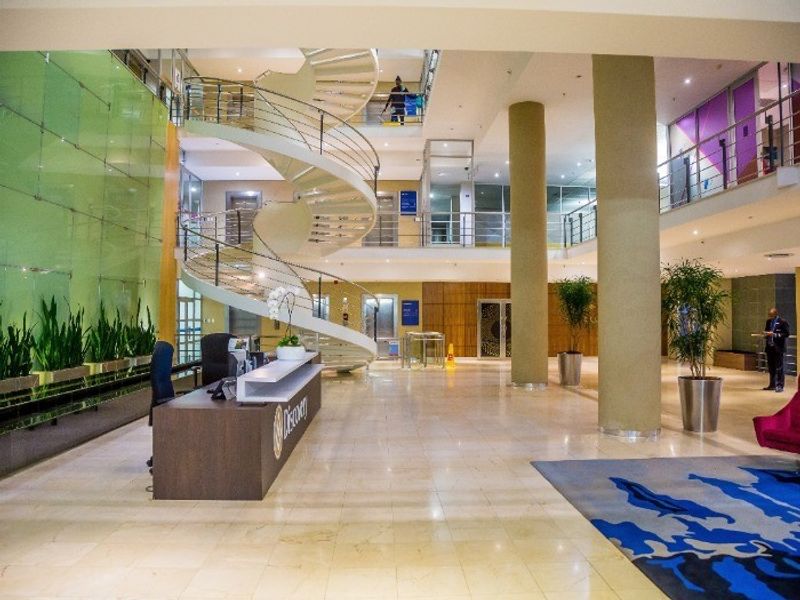 Spacious commercial lobby featuring a prominent spiral staircase, marble flooring, structural columns, and a modern reception area with glass architectural elements.