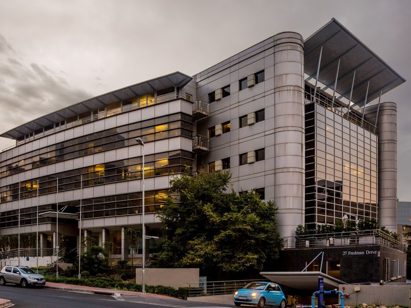 Modern multi-story commercial office building featuring a glass curtain wall, metal facade cladding, and a prominent cantilevered roof structure at 27 Fredman Drive.