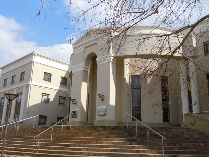 Front elevation of a commercial building featuring a grand stone staircase leading to an arched entrance portico with architectural columns.