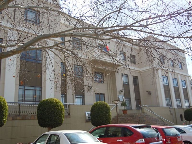 Front elevation of a multi-story commercial building featuring large windows, stone steps, and architectural detailing.