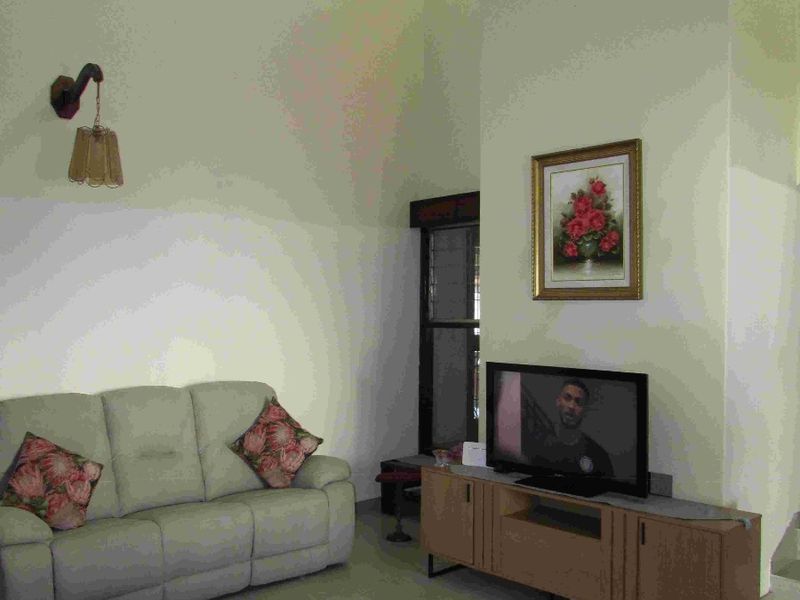 A living room featuring high vaulted ceilings, tiled flooring, and a wall-mounted light fixture, offering a spacious and bright atmosphere.