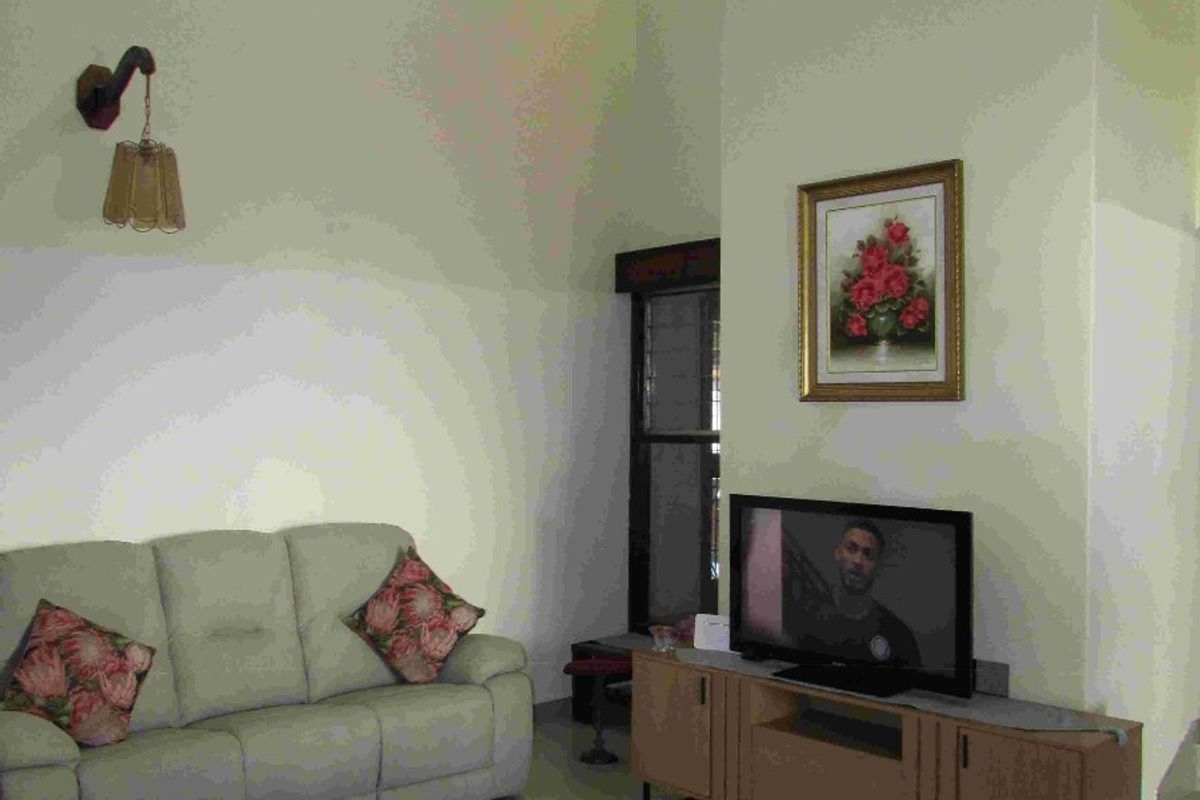 A living room featuring high vaulted ceilings, tiled flooring, and a wall-mounted light fixture, offering a spacious and bright atmosphere.