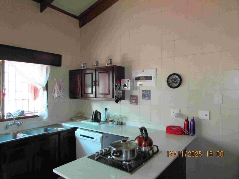 A functional kitchen featuring built-in cabinetry, a hob, and tiled splashbacks. The space offers a practical layout with integrated sink and utility fixtures.