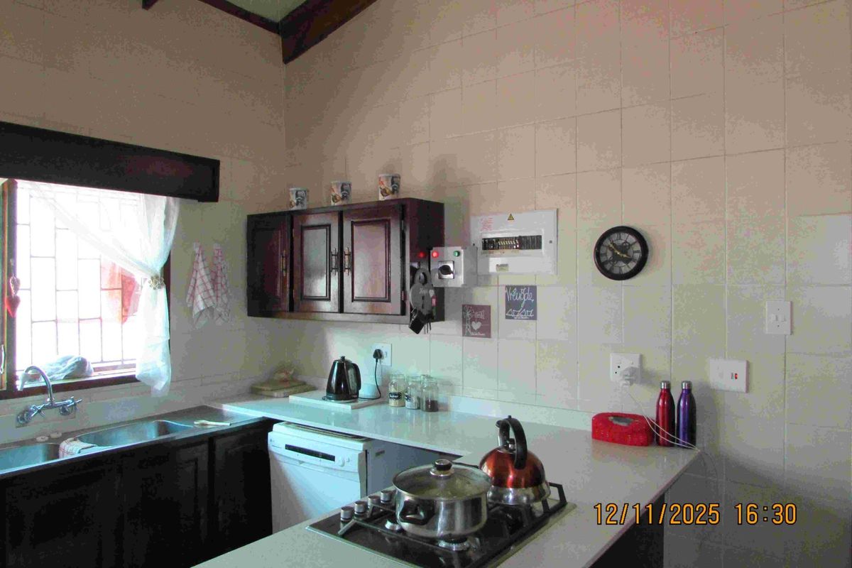 A functional kitchen featuring built-in cabinetry, a hob, and tiled splashbacks. The space offers a practical layout with integrated sink and utility fixtures.