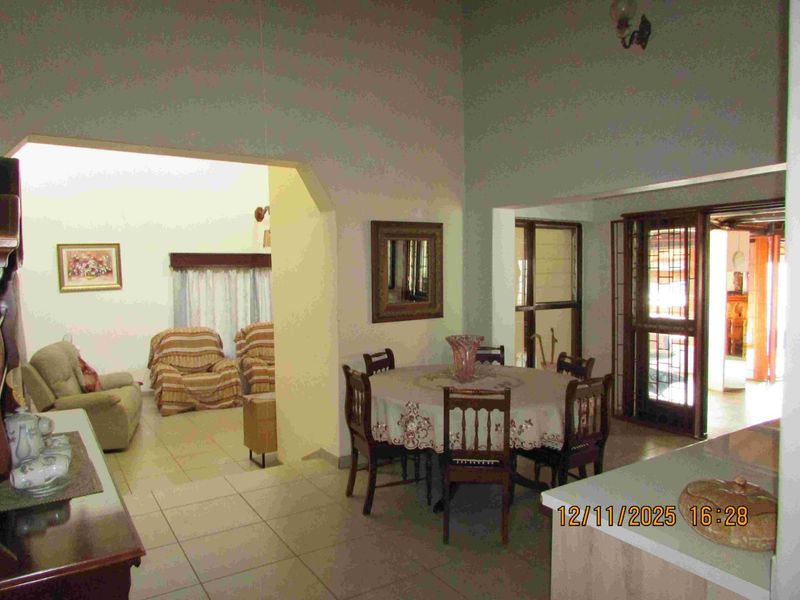 Open plan living and dining area featuring tiled floors and vaulted ceilings with access to an outdoor patio area.