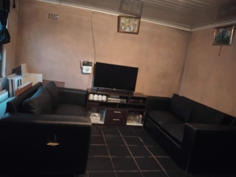 A living room featuring dark tiled flooring and textured walls, requiring cosmetic updates to improve the overall finish and aesthetic appeal.