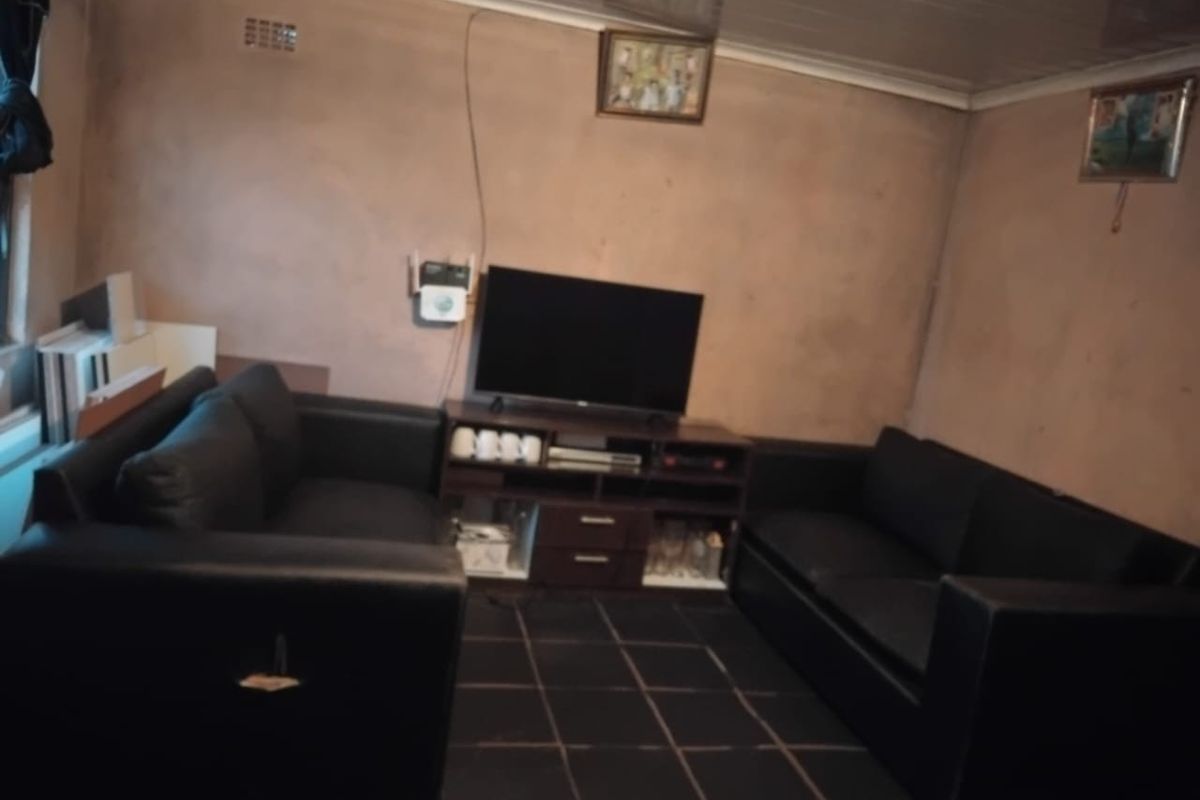 A living room featuring dark tiled flooring and textured walls, requiring cosmetic updates to improve the overall finish and aesthetic appeal.