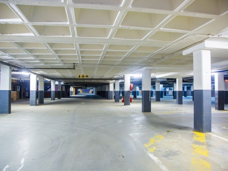 Spacious underground commercial parking garage featuring a waffle slab ceiling, concrete support columns, and fire safety equipment.
