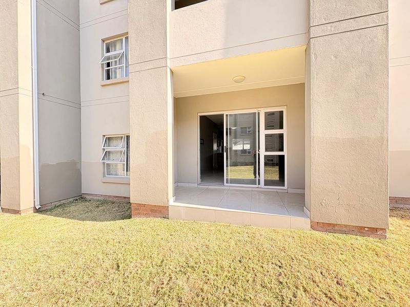 A ground floor patio area featuring tiled flooring and a sliding glass door entrance, providing direct access to the surrounding garden space.