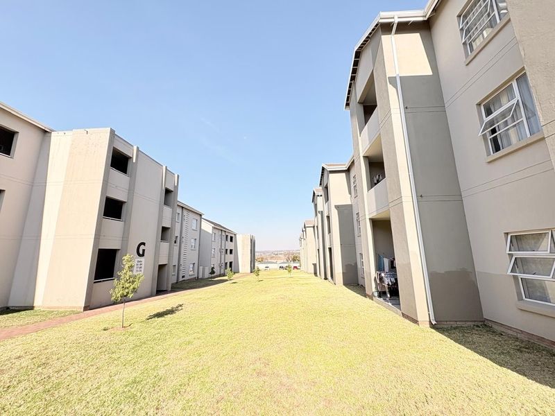 View of the exterior grounds between multi-story apartment blocks, featuring well-maintained lawns and paved walkways within the residential complex.