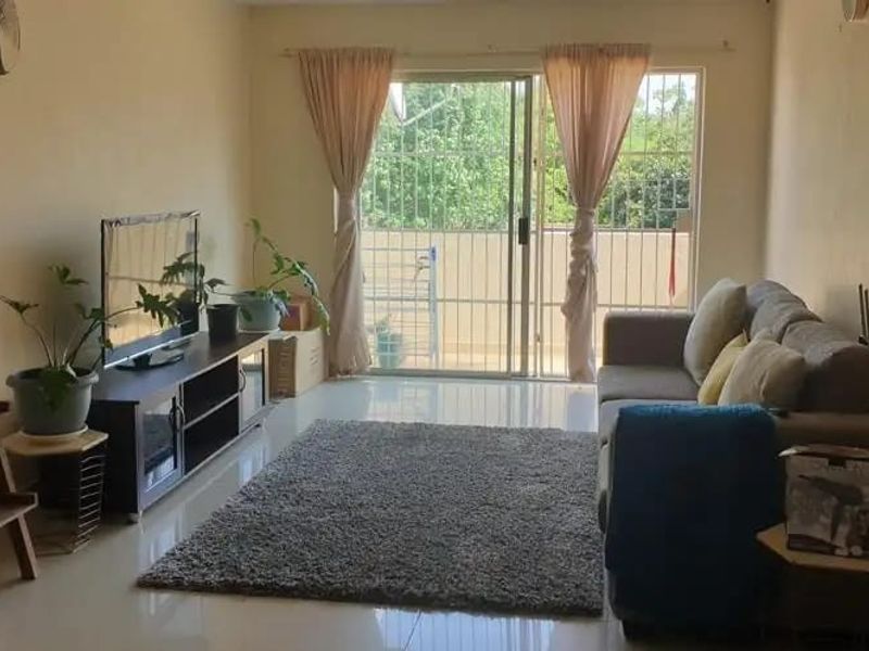 A living room featuring tiled flooring and a sliding glass door with security gate, providing access to an outdoor area.