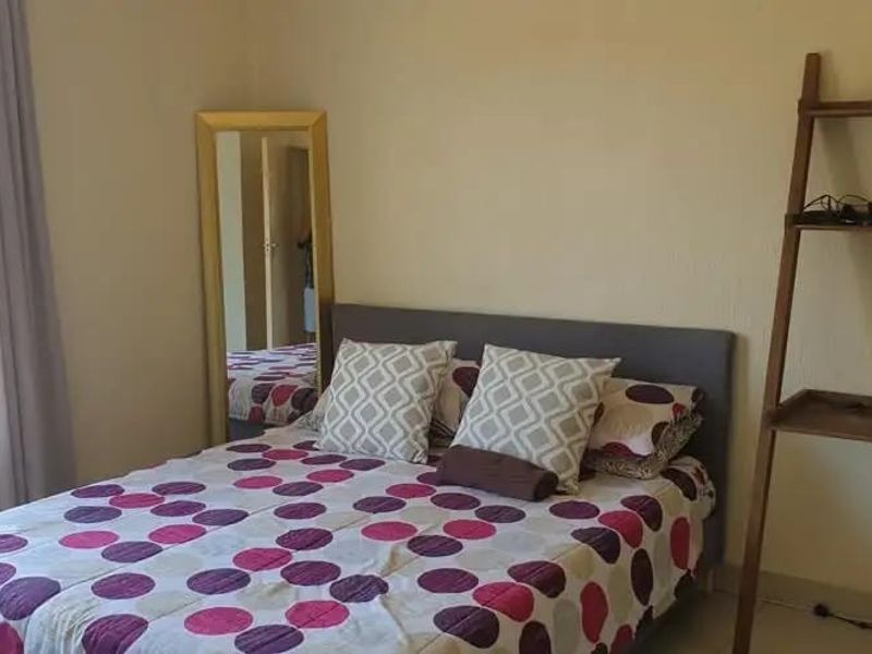 A functional bedroom featuring a window with security bars and standard electrical outlets.