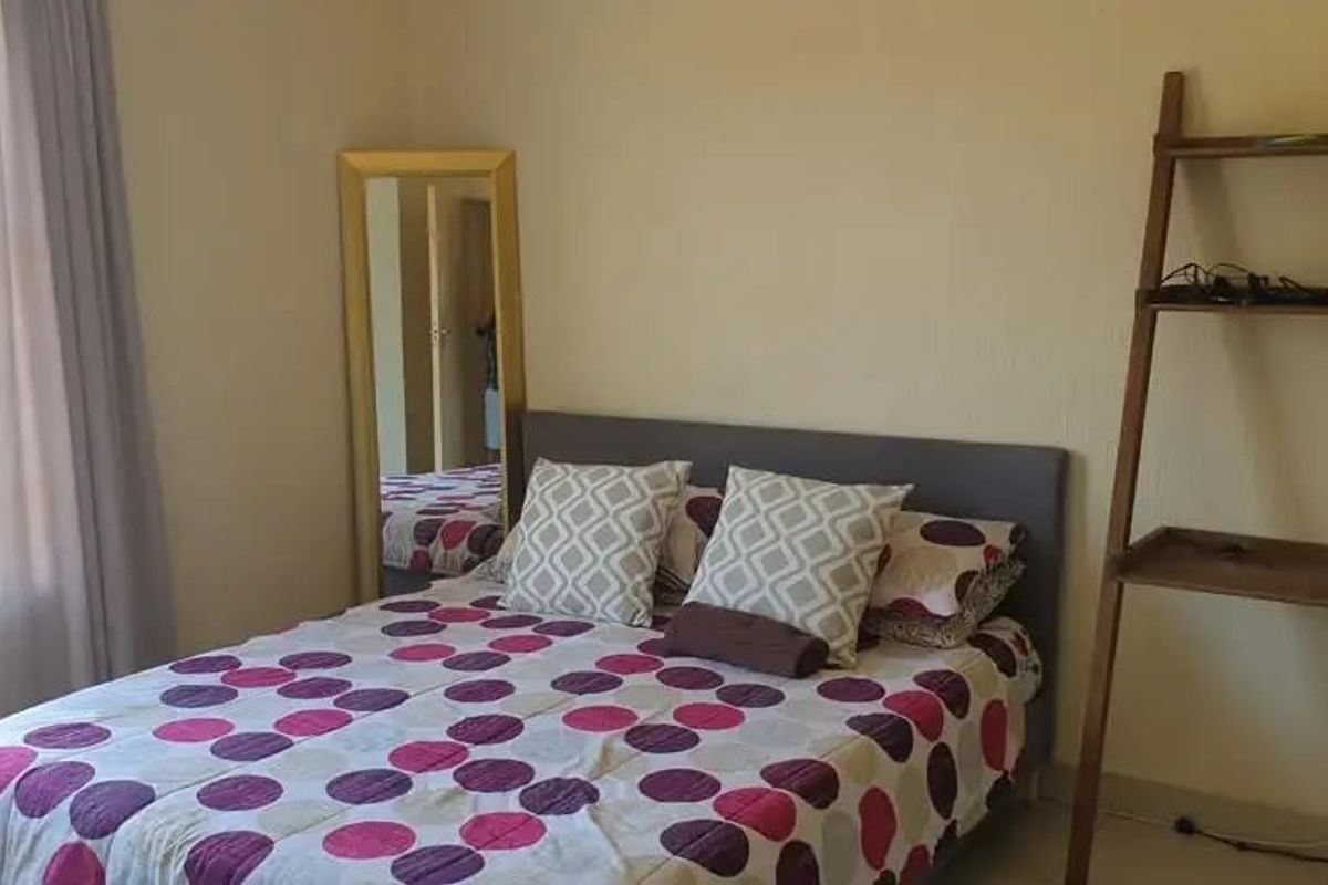 A functional bedroom featuring a window with security bars and standard electrical outlets.