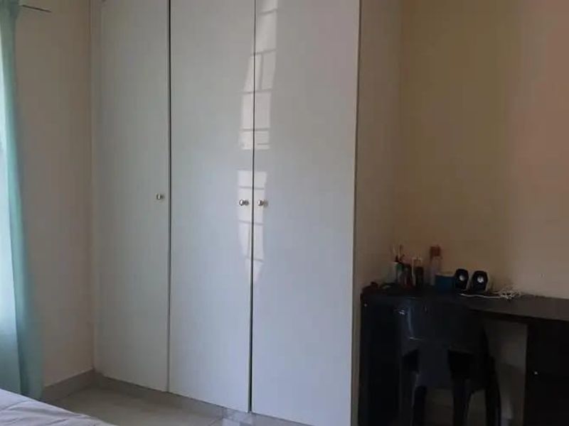 A functional bedroom featuring white built-in cupboards and neutral wall finishes, offering a clean and practical living space.