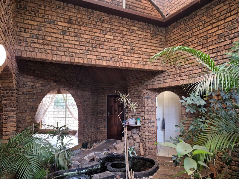 A unique, semi-enclosed courtyard area featuring exposed brickwork, arched architectural details, a built-in water feature, and a skylight providing natural light.