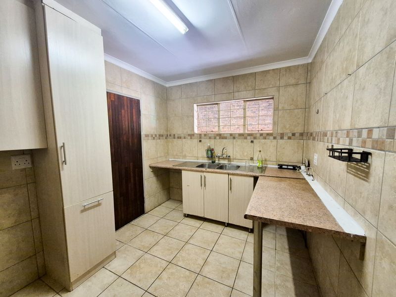 A functional scullery area featuring built-in cabinetry, double sink, and tiled finishes, providing a practical space for food preparation and wash-up.