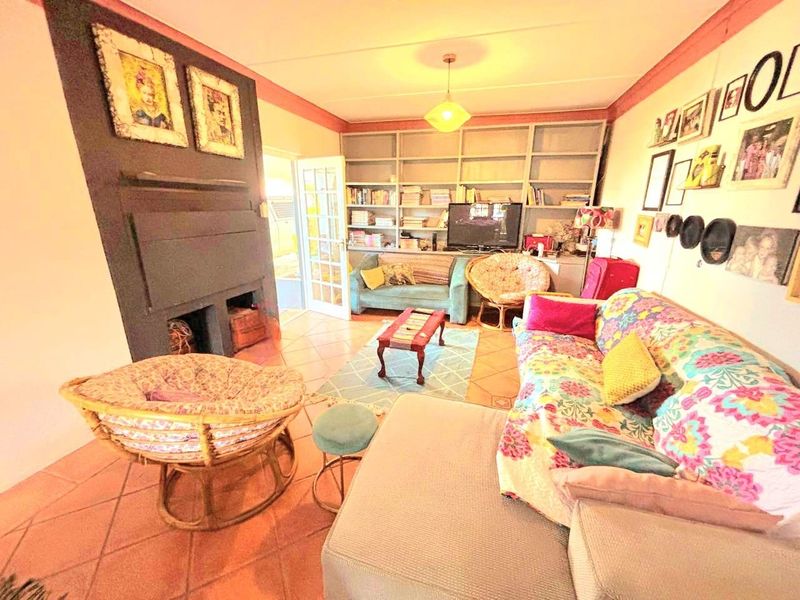 A cozy living room featuring a built-in fireplace, extensive wall-to-wall shelving, and tiled flooring, offering a warm and functional space.