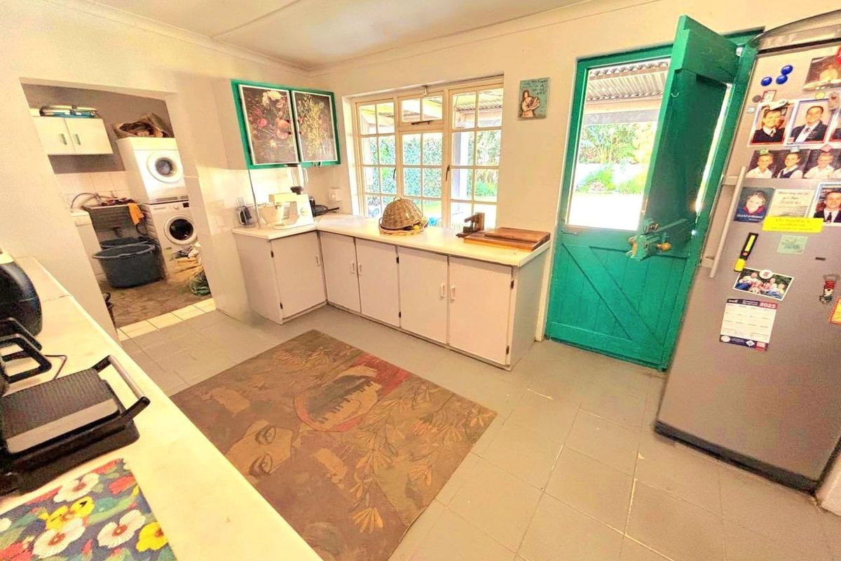 A functional kitchen featuring built-in cabinetry, tiled flooring, and an adjoining scullery area with direct access to the exterior via a stable door.