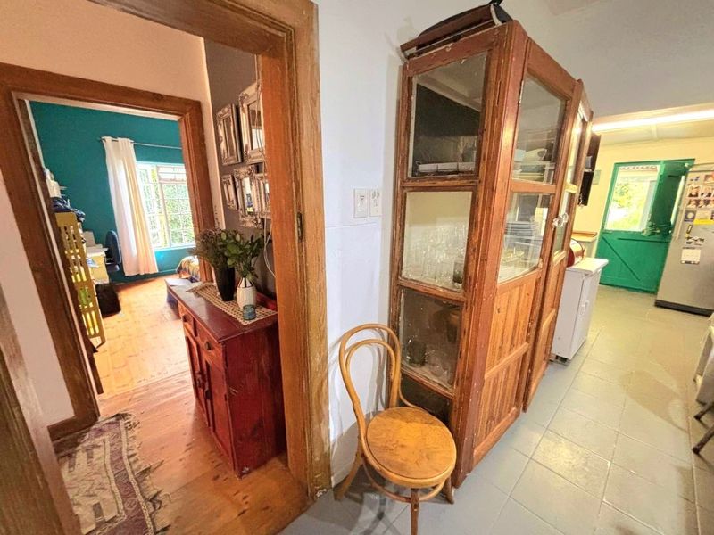 A transitional hallway area connecting multiple rooms, featuring a mix of timber and tiled flooring with access to an exterior stable-style door.