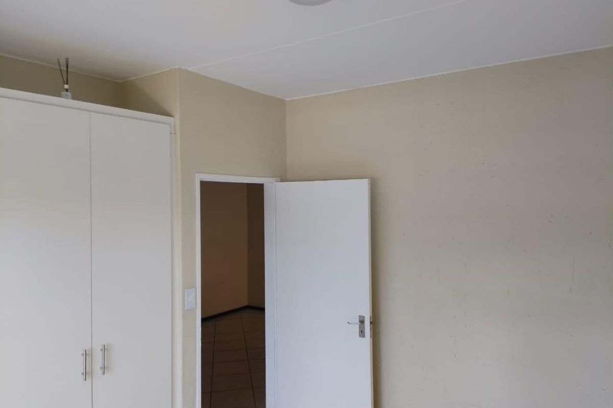 A simple, empty bedroom featuring a built-in wardrobe and neutral wall finishes, offering a blank canvas for personalization.